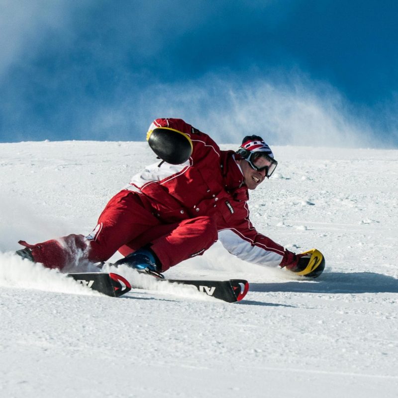 pexels-photo-1271147-1271147 A skier in vibrant red gear skillfully navigates a snowy slope on a sunny day.