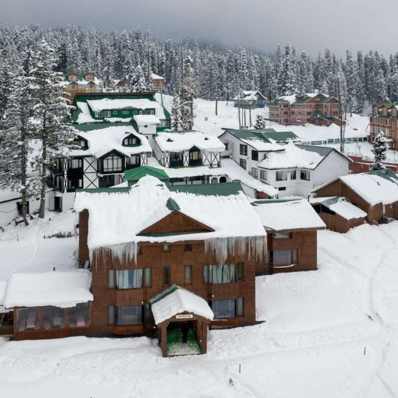 pexels-photo-15232505-15232505 Aerial view of snow-covered chalets in Gulmarg during winter.