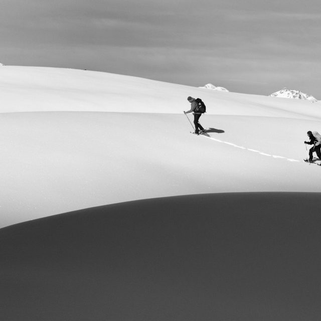 pexels-photo-28321650-28321650 Two hikers trekking uphill in a snowy mountain landscape, capturing the essence of winter adventure.