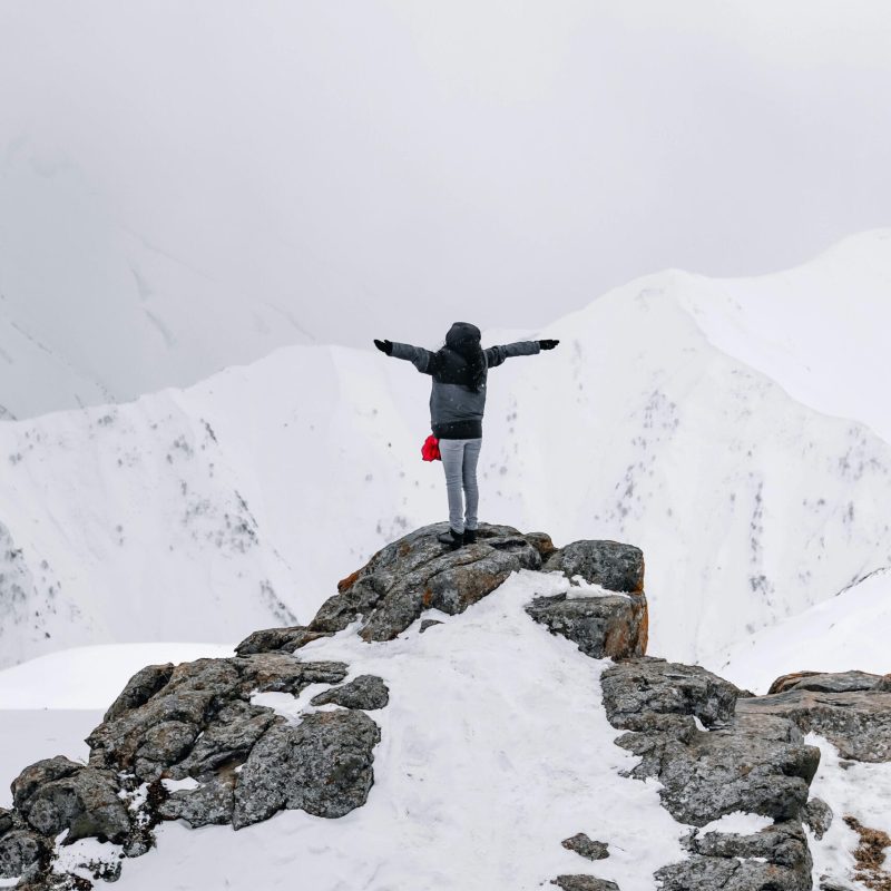 pexels-photo-7113999-7113999 A lone figure enjoys the winter view from a snowy mountain summit.